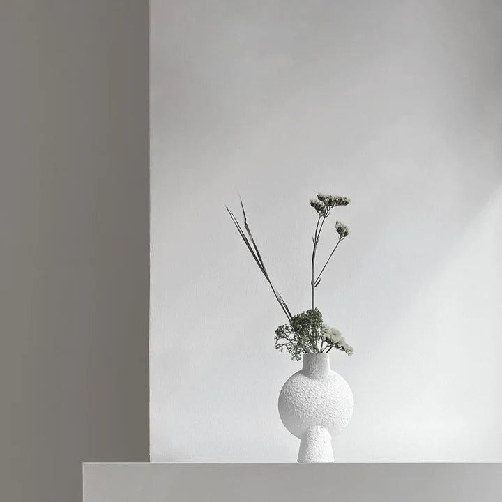 A 101Cph Sphere Vase Bubl Mini Bubble White 202003 by 101 Copenhagen, a Scandinavian brand, sits on a shelf in a room.