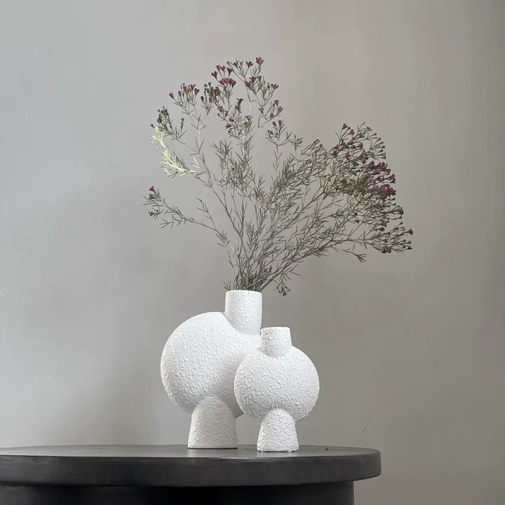 Two white 101 Copenhagen Sphere Vases from the popular Scandinavian brand, Mini Bubble White, sitting elegantly on a black table.