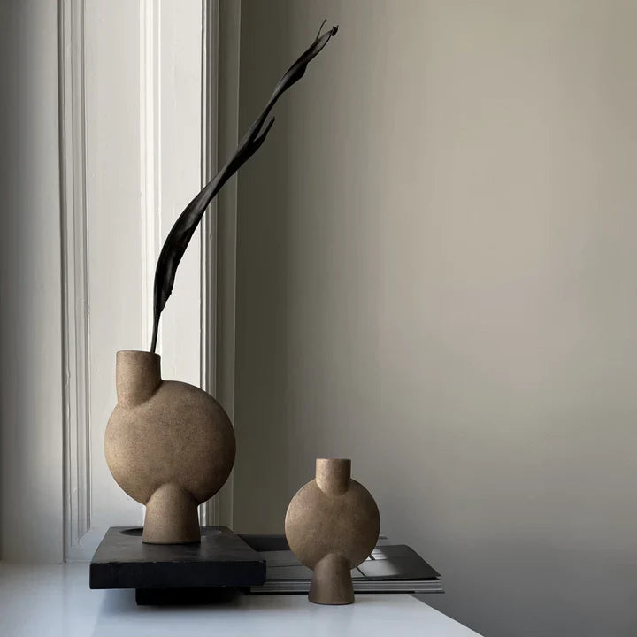 Two 101 Copenhagen 101Cph Sphere Vase Bubble Mini Ocher 111180 vases, proudly displayed on a shelf, adding a touch of Scandinavian style to the room with their elegant design.