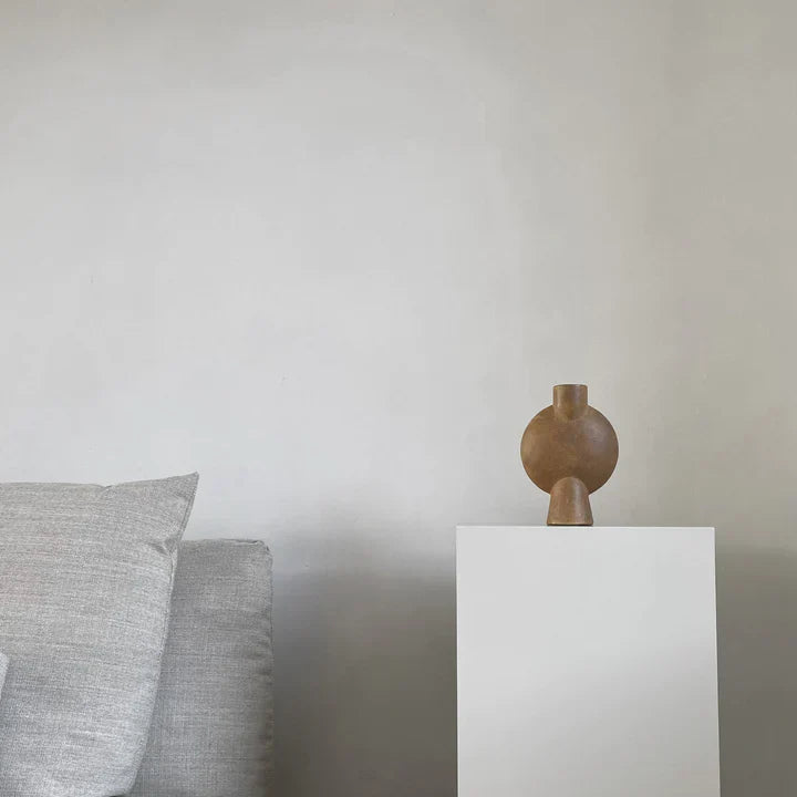 A 101 Copenhagen brand's 101Cph Sphere Vase Bubl Mini Ocher 111180 sits on top of a white pedestal.