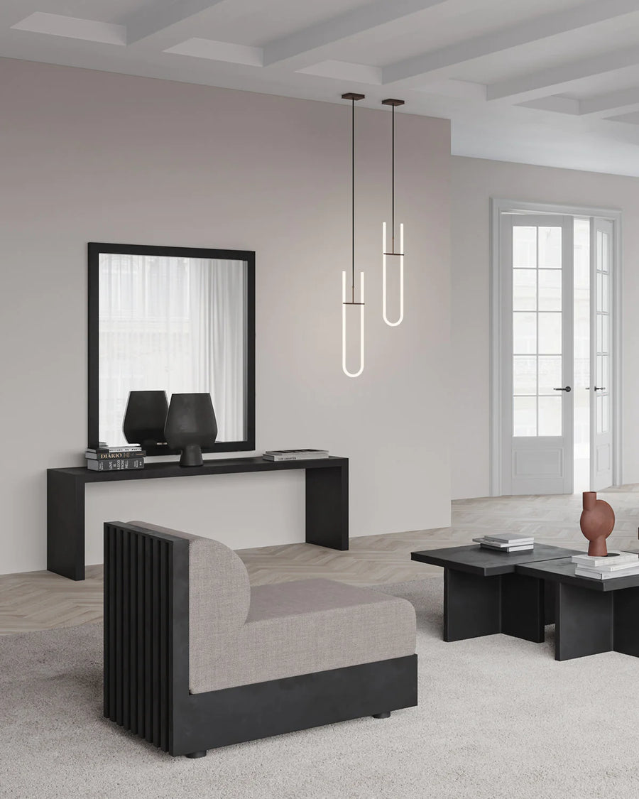 This modern living room features black furniture, including the 101Cph Sphere Vase Square Big Coffee 111183 from the Sphere collection, by the 101 Copenhagen brand. A mirror adds to the contemporary aesthetic.