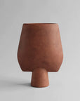 A 101Cph Sphere Vase Square Big Terracotta 212008 vase by 101 Copenhagen on a grey background.