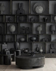 A room with many black 101Cph Sphere Vase Square Mini Dark Grey 111020 vases from the Sphere collection by the Scandinavian brand 101 Copenhagen. The vases are displayed on a coffee table.