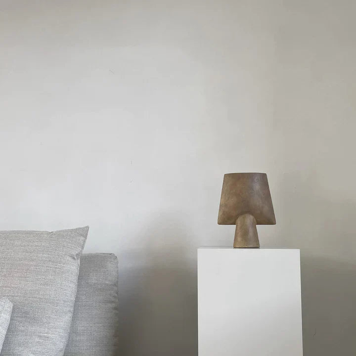 A white couch with a lamp on top of it, accented by an elegant 101Cph Sphere Vase Square Mini Ocher 111181 from 101 Copenhagen.