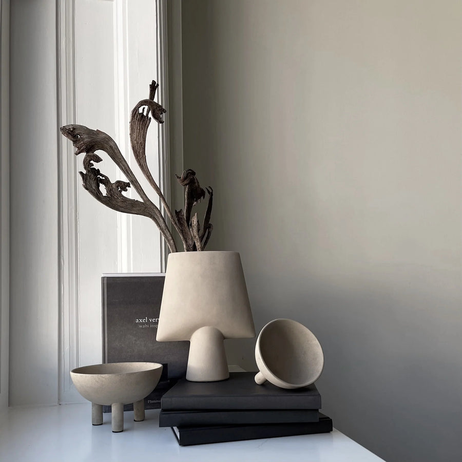 Decorative items including a vase, books, and a cup on a surface with a neutral background.
