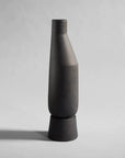 A black 101Cph Sphere Vase Tall Coffee 111205 on a grey background by the Scandinavian brand, 101 Copenhagen.