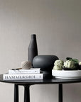 A black table with a 101Cph Sphere Vase Tall Coffee 111205 by 101 Copenhagen on it.