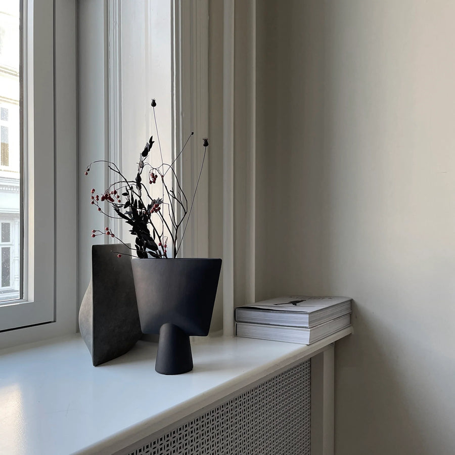 A collection of 101 Copenhagen vase and home accessories on a window sil with artifical foliage and coffee table books in a luxury modern interiors. Styled by Spacio Inteiror Styling team. 