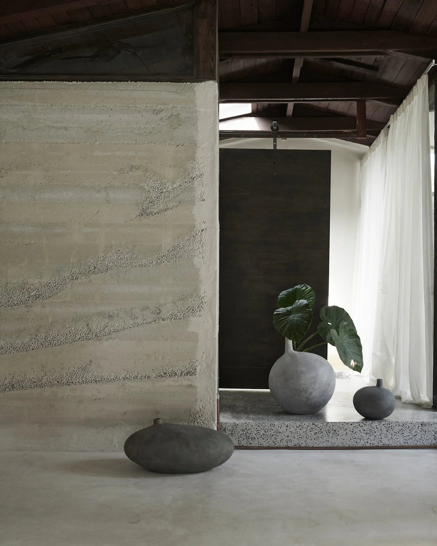 Minimalist interior with stone walls, a plant, and decorative vases from 101 Copenhagen at Spacio retail stores in Mumbai & Kolkata. 