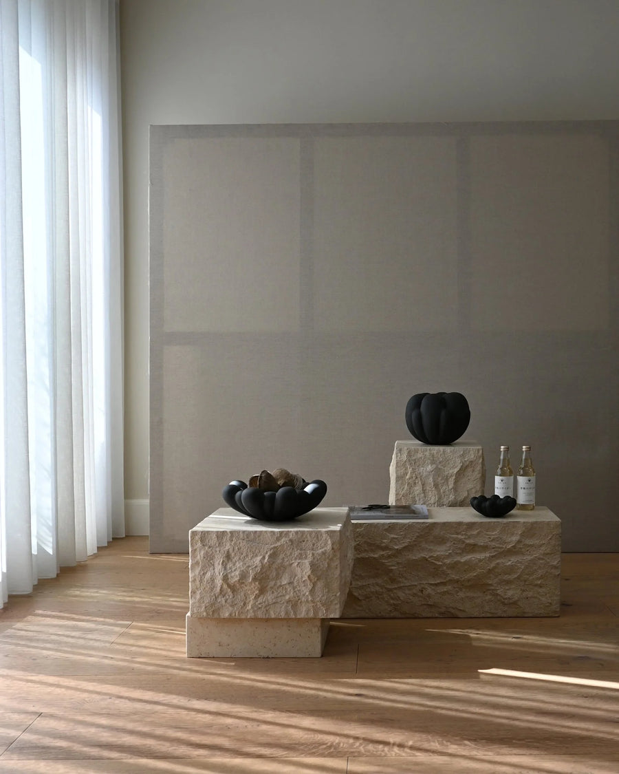Modern interior with limestone plinth and decorative items against a plain wall.