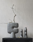 Three 101Cph Tribal Vase Medio Dark Grey 214003s by 101 Copenhagen on a table next to a fireplace. Available at Spacio India