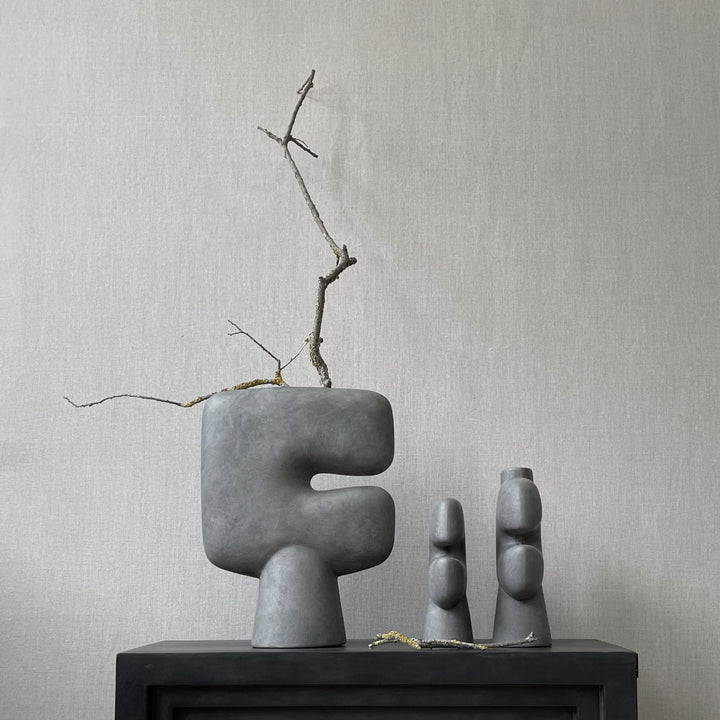 Three 101Cph Tribal Vase Medio Dark Grey 214003s by 101 Copenhagen on a table next to a fireplace. Available at Spacio India