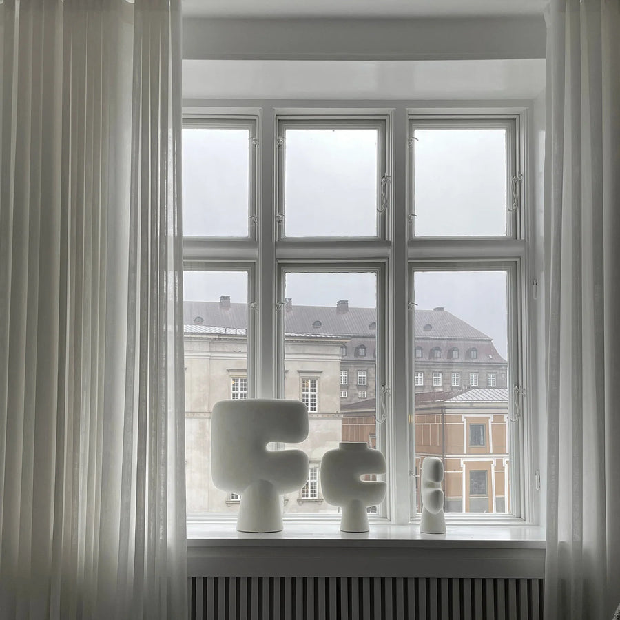Decorative vases on a windowsill with a view of buildings outside