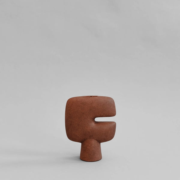 A terracotta finish sculptural vase on a light gray background from 101 Copenhagen at Spacio retail stores in Mumbai & Kolkata. 