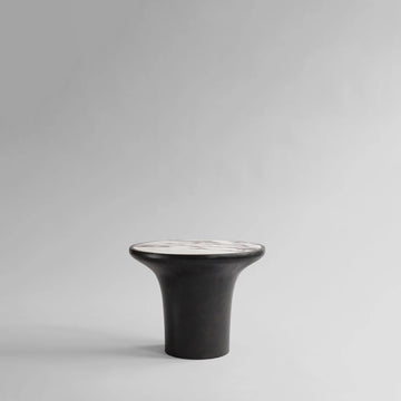 Black ceramic side table with white calacatta marble top on a gray background from 101 Copenhagen at Spacio retail stores in Mumbai & Kolkata. 