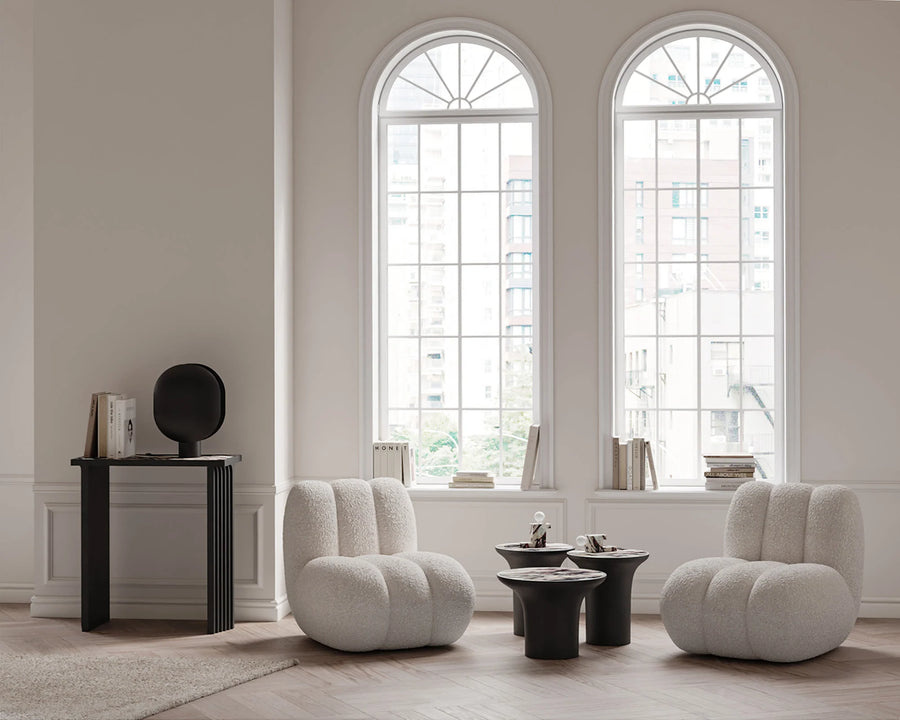 Modern living room with two white armchairs and a calacatta top coffee table in front of large windows.
