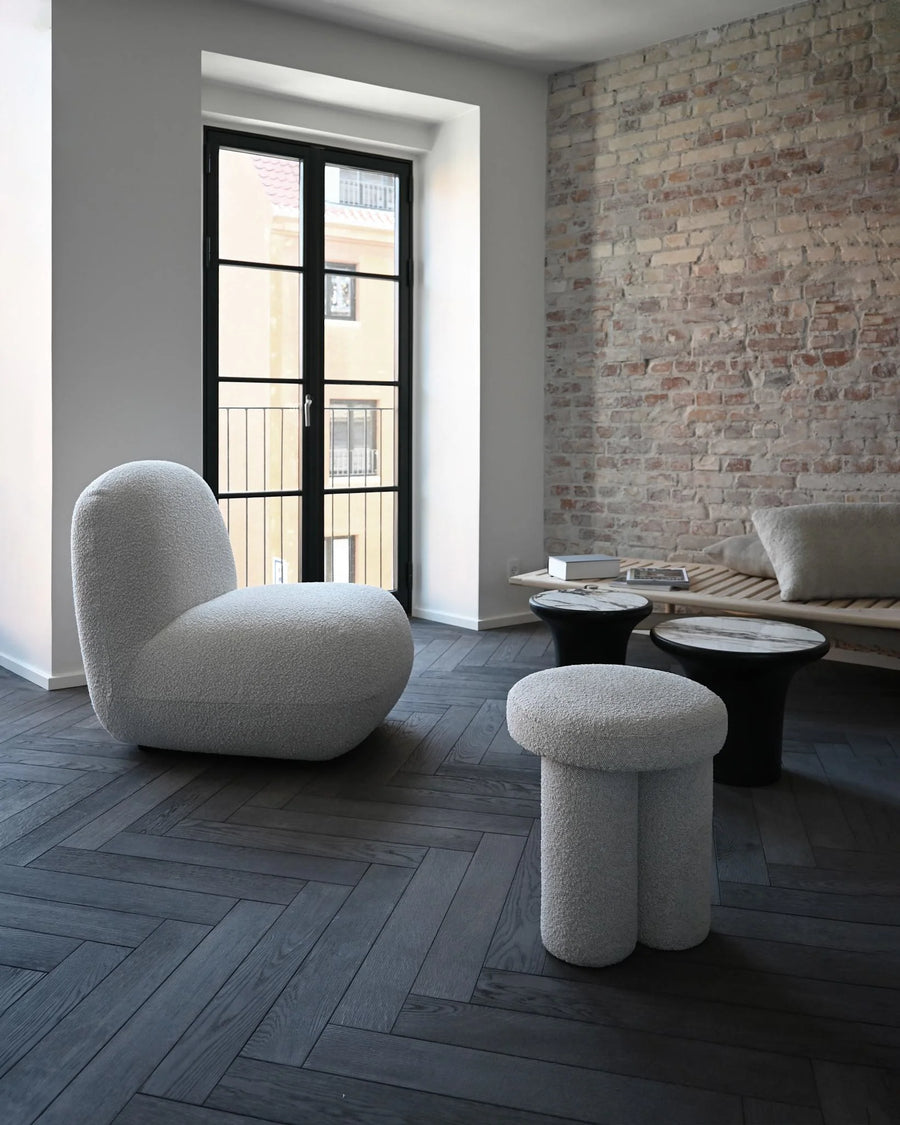 Modern living room with a textured wall, gray floor, and stylish furniture.
