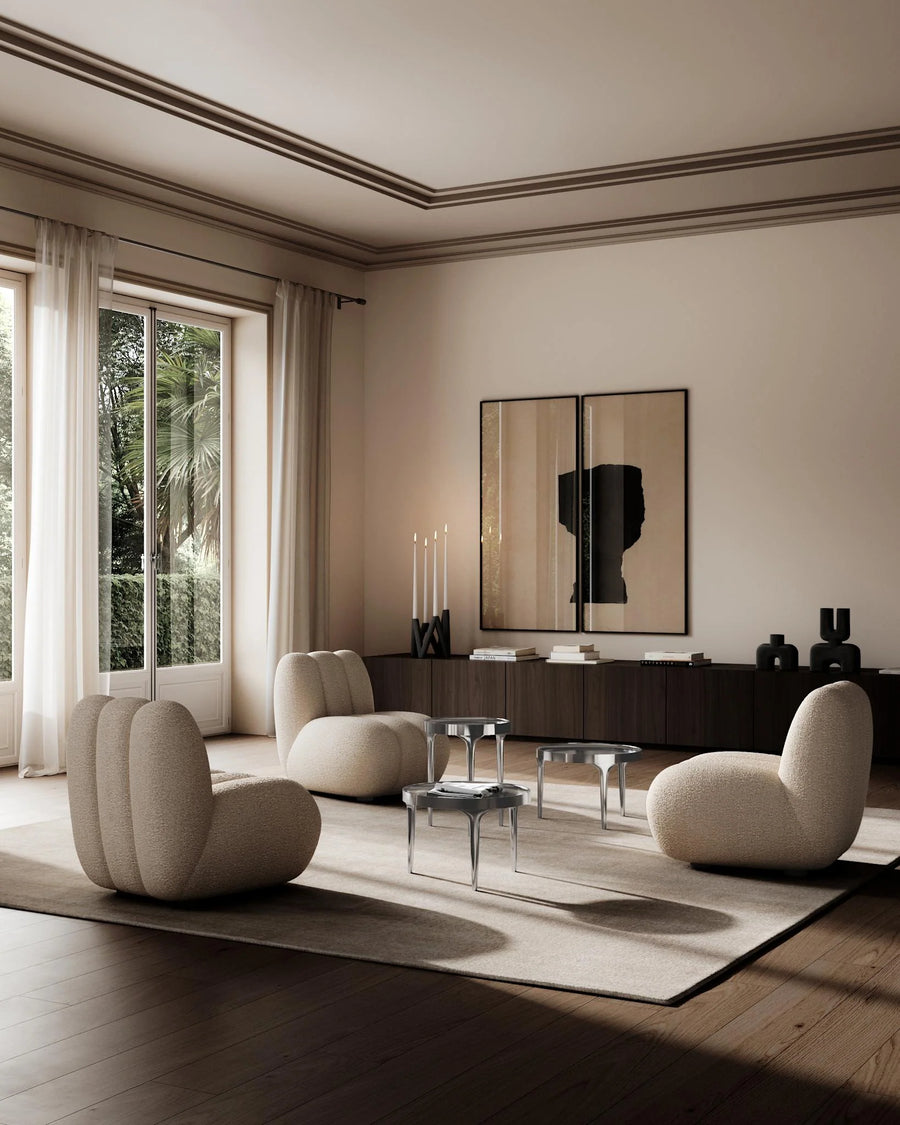 Modern living room with beige chairs, a coffee table, and a large mirror on the wall.