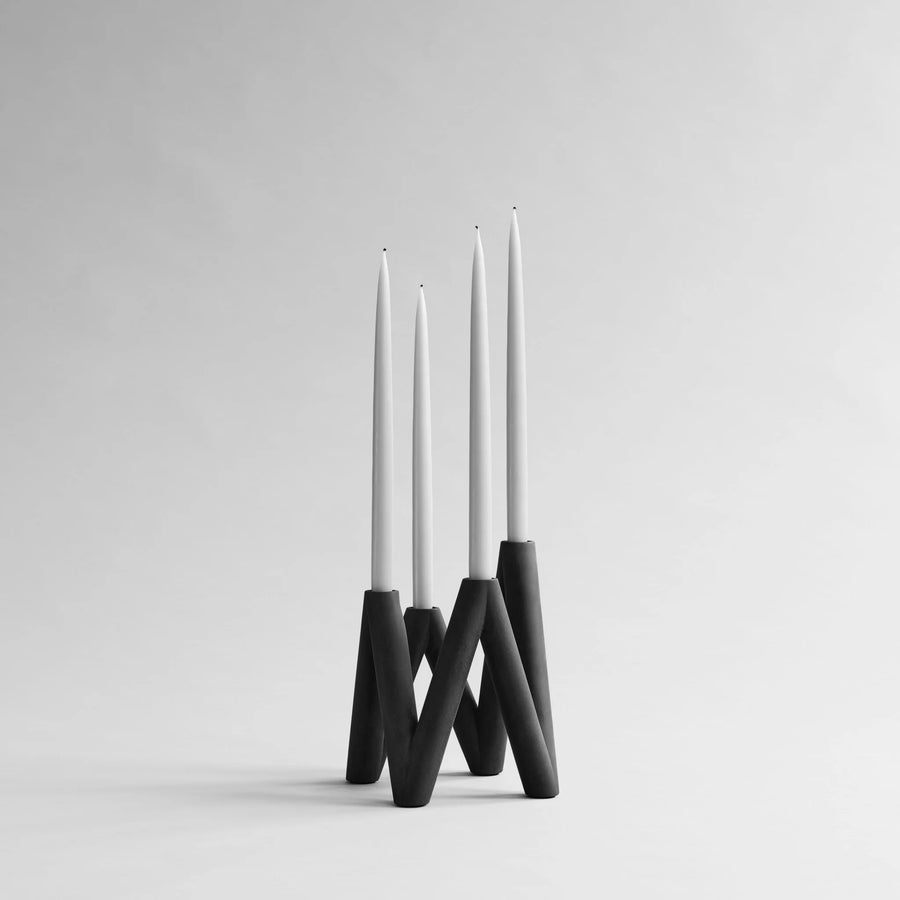 Modern black candle holder with three white candles on a gray background from 101 Copenhagen at Spacio retail stores in Mumbai & Kolkata. 