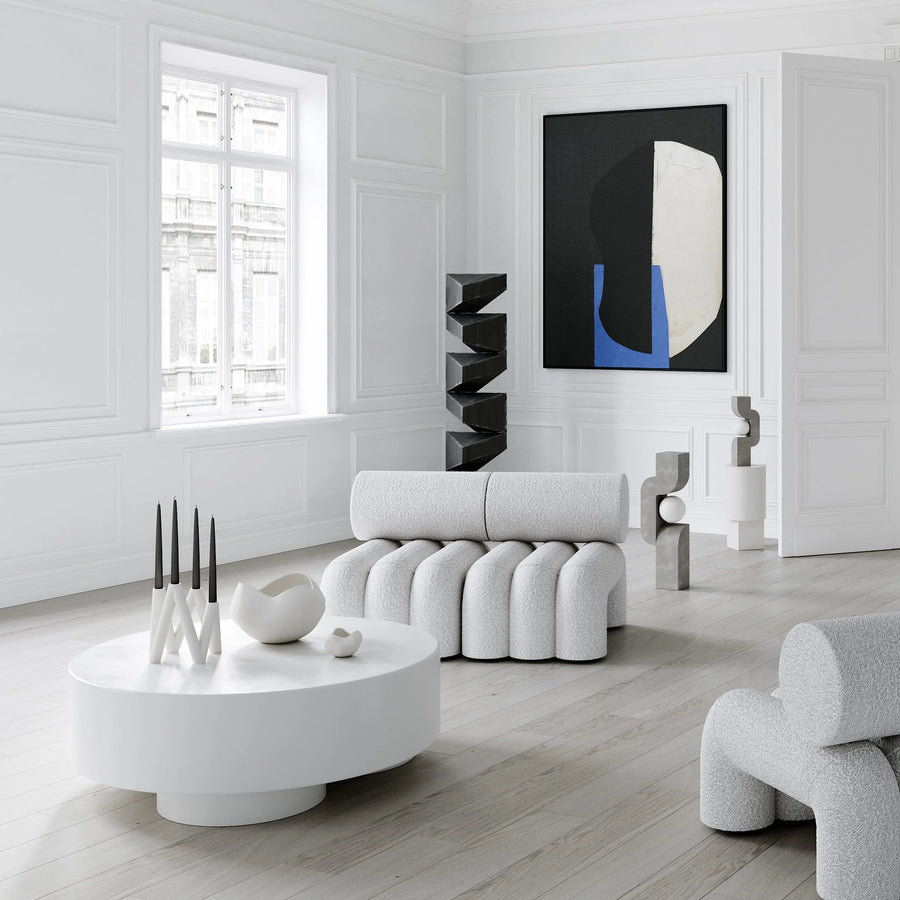 Modern living room with white furniture, abstract art, and a round coffee table.