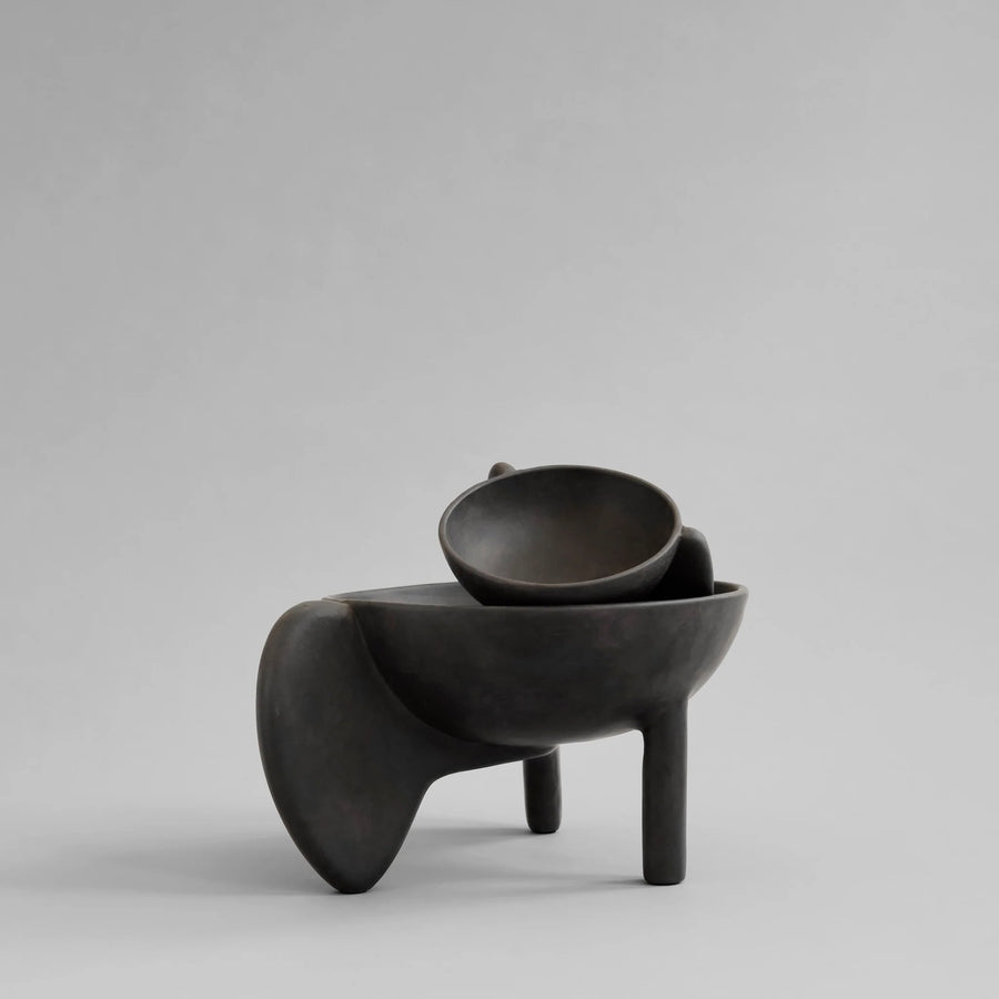 Black ceramic bowl on a gray background from 101 Copenhagen at Spacio retail stores in Mumbai & Kolkata. 