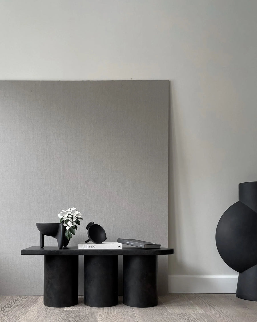 Modern black table with decorative items against a gray wall from 101 Copenhagen at Spacio retail stores in Mumbai & Kolkata. 