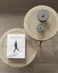 Round woven coffee table with a book titled 'The Kinfolk Entrepreneur' on a wooden floor from 101 Copenhagen at Spacio retail stores in Mumbai & Kolkata. 