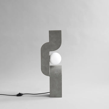 Modern concrete table lamp with a white bulb on a gray background from 101 Copenhagen at Spacio retail stores in Mumbai & Kolkata. 
