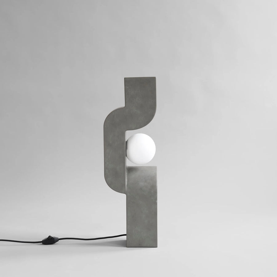 Modern concrete table lamp with a white bulb on a gray background from 101 Copenhagen at Spacio retail stores in Mumbai & Kolkata. 