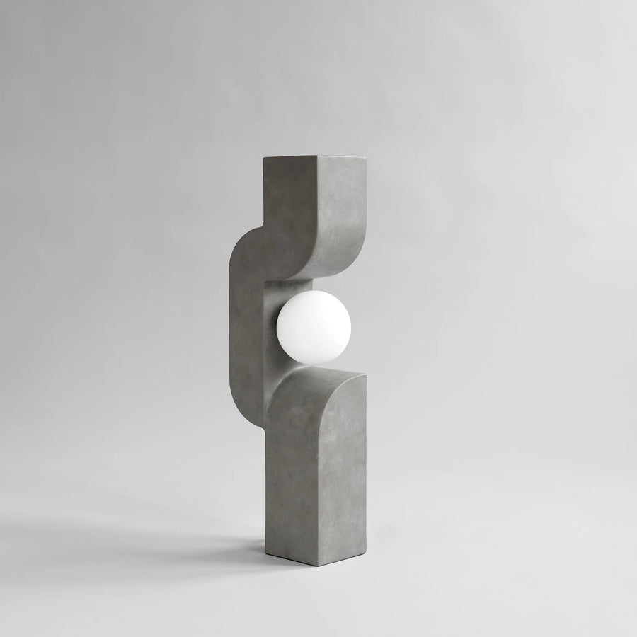 Concrete lamp with a spherical light bulb on a gray background from 101 Copenhagen at Spacio retail stores in Mumbai & Kolkata. 