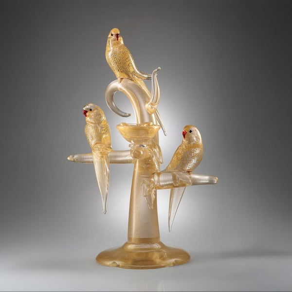 Glass sculpture of three parrots on a branch against a gray background by Zanetti at Spacio in India. 