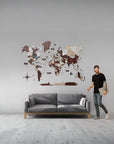 Man standing next to a gray sofa with a XL size world map wall decoration on a gray wall.