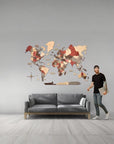 Man standing next to a XL size wooden world map wall in a living room.