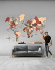 Man standing next to a 3XL world map wall decoration in a room with a gray sofa.