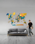 Man standing next to a colorful XL size world map wall art in a living room.