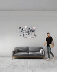 Man standing next to a gray sofa with a medium size world map wall art in a minimalistic room.