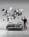 Man standing next to a world map wall art in a living room setting.