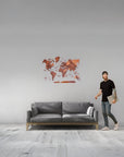 Man standing next to a gray sofa with a medium size world map wall decoration in a minimalistic room.