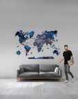 Man standing next to a world map wall decal in a living room.