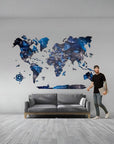 Man standing next to a world map wall decal in a room with a gray sofa.