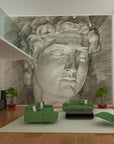 Charcoal fresco mural of Michelangelo’s David, crafted on Italian plaster with Carrara marble and travertine powder, showcasing timeless classical beauty. Featured in a double height luxury living room in front of a green sofa