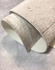 Roll of textured wallpaper on a gray surface