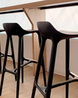 A row of European luxury black Agrippa Morgan bar stools in front of a window.