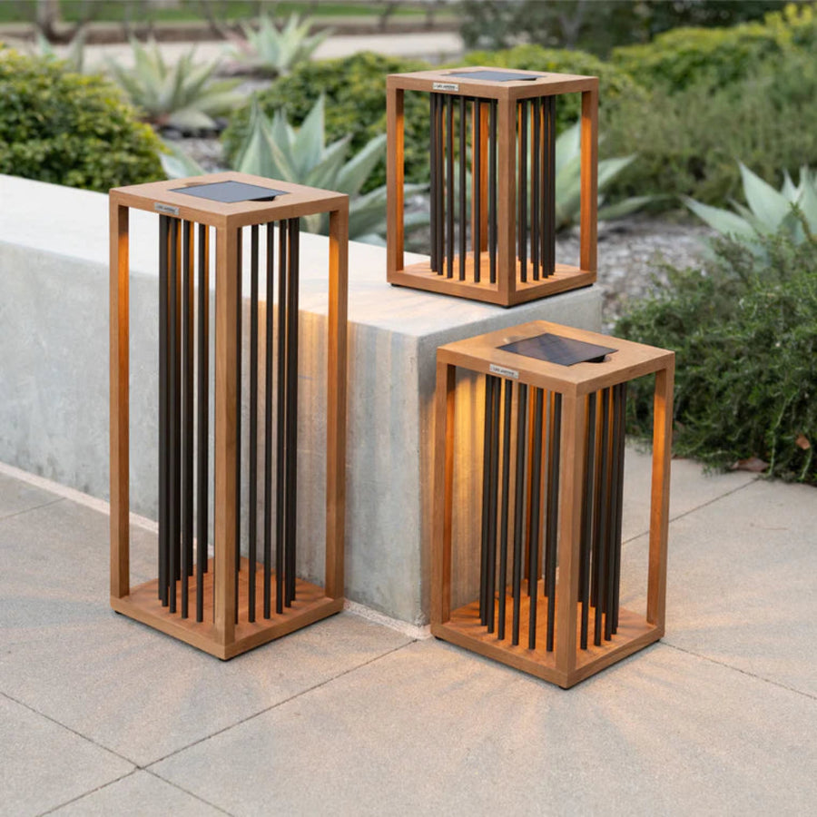 Three wooden outdoor solar lantern lamps with metal accents on a stone surface by Les Jardins available at Spacio retail stores in Mumbai & Kolkata. 