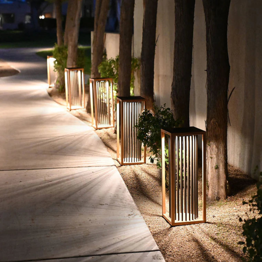 Decorative outdoor solar lanterns along a pathway with plants and a building in the background by Les Jardins available at Spacio retail stores in Mumbai & Kolkata. 