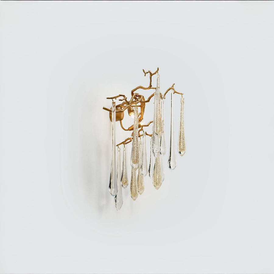 Side view of a wall light with glass droplets in clear and gold colour hanging from gold finish branches on a light grey colour background