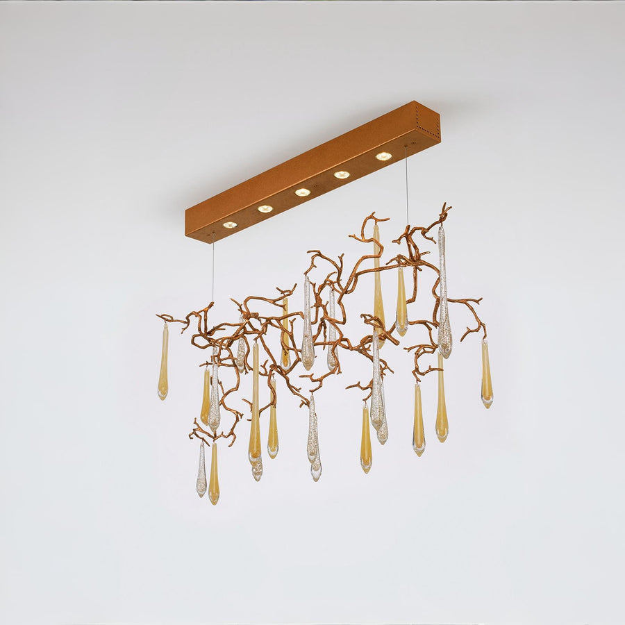 A ceiling chandelier with water droplets in gold colour glass hanging on gold colour branches. 
