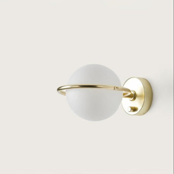 A round wall light with brass detailing on a cream colour background. 