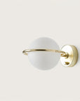 A round wall light with brass detailing on a cream colour background. 