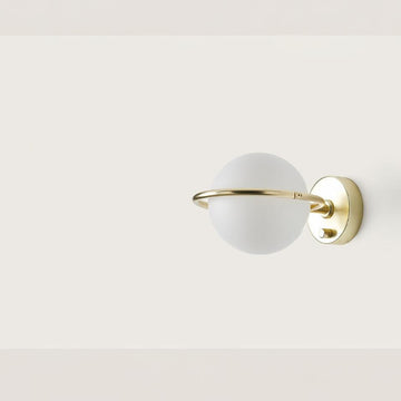 A round wall light with brass detailing on a cream colour background. 